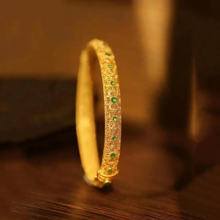 Bracelet en style jonc avec des pierres précieuses vertes dorées et un motif floral de style ethnique